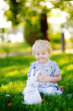 Paskalya günü bahar bahçesinde Paskalya yumurtası arayan küçük bir çocuk.
