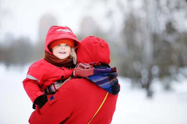 Portret van mooi klein kind en zijn moeder in besneeuwde park — Stockfoto