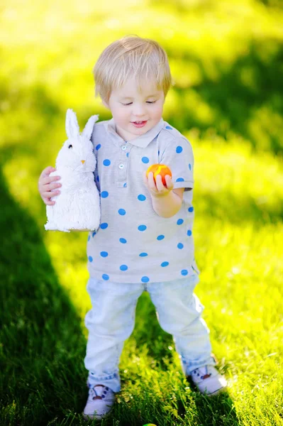 Malý chlapec loví velikonoční vejce v jarní zahradě o velikonočním dni — Stock fotografie