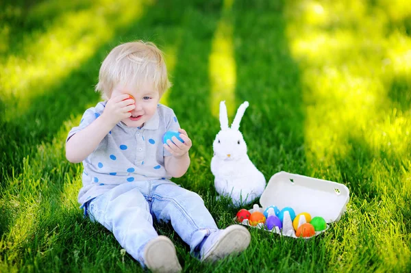 Mały chłopiec poluje na pisanki w wiosennym ogrodzie w Wielkanoc — Zdjęcie stockowe