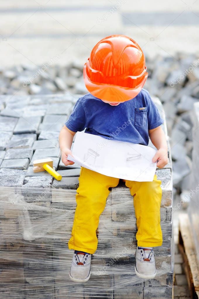 Portrait of little builder in hardhats reading construction drawing