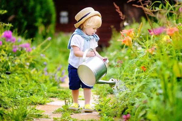 Ładny toddler chłopiec w słomkowym kapeluszu podlewania roślin w ogrodzie — Zdjęcie stockowe