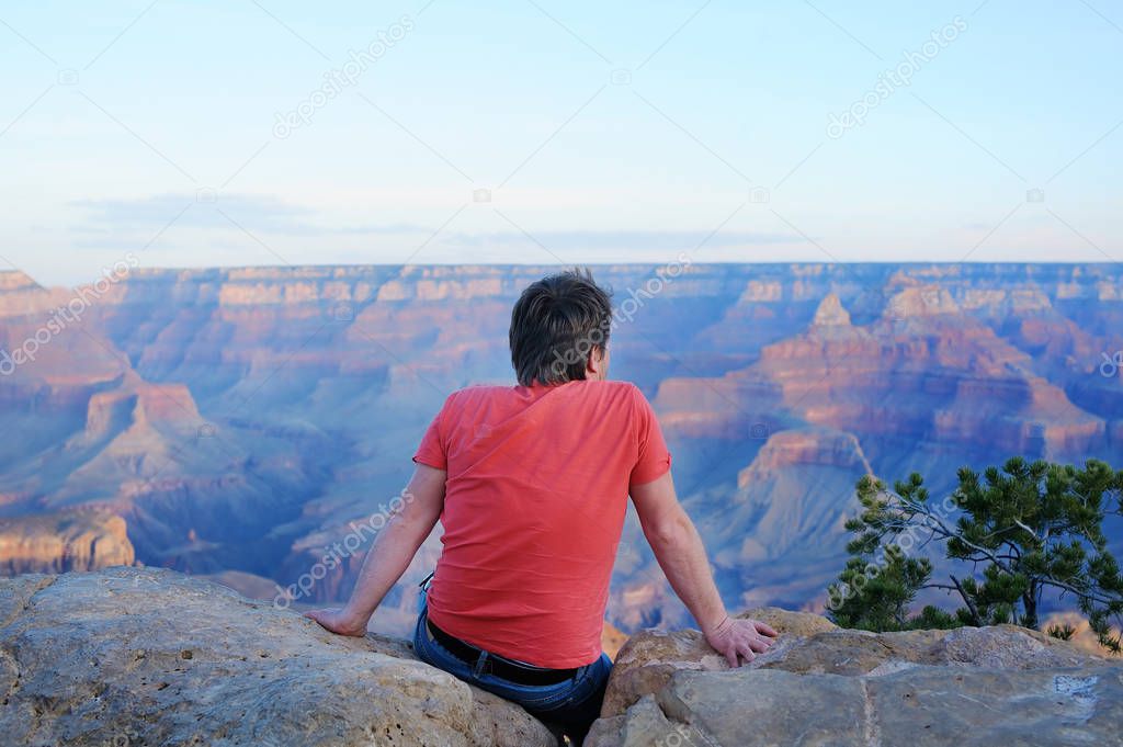 Man sitting on stone and looking of the Grand Canyon