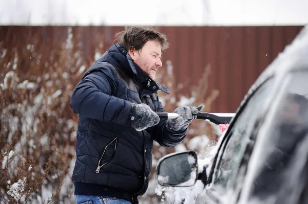 中年男のブラシを使用して車から雪の清掃 — ストック写真