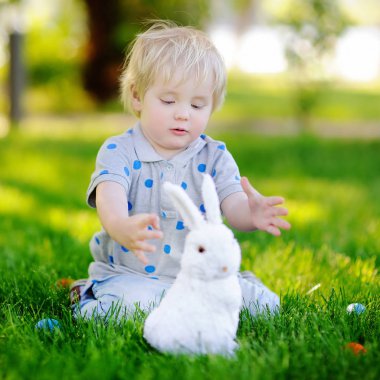 Paskalya günü bahar bahçesinde Paskalya yumurtası arayan küçük bir çocuk.