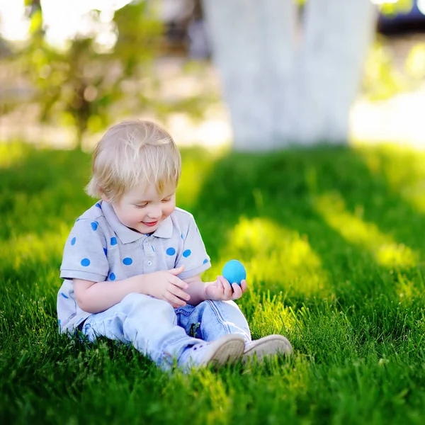 Liten pojke jakt på påskägg i vår trädgård på påskdagen — Stockfoto