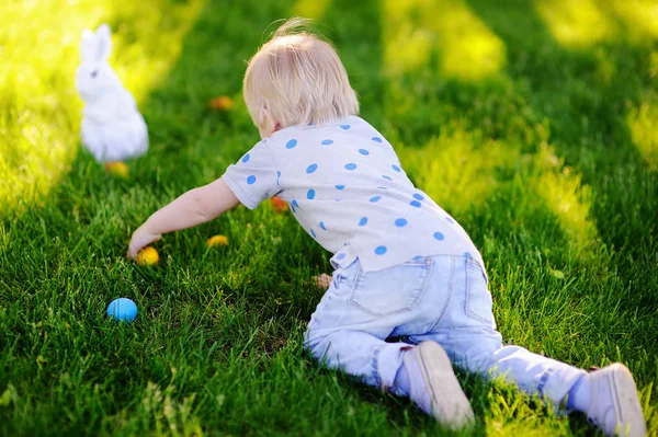 Bambino a caccia di uova di Pasqua nel giardino primaverile il giorno di Pasqua — Foto Stock