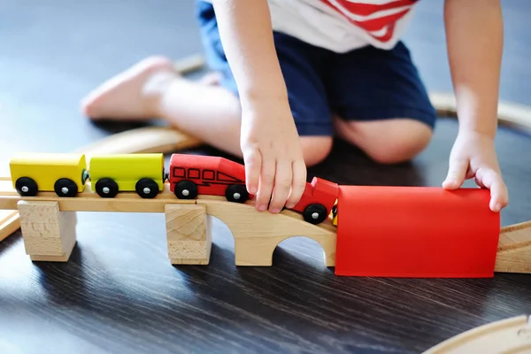 Маленький мальчик играет с игрушечным деревянным поездом дома — стоковое фото