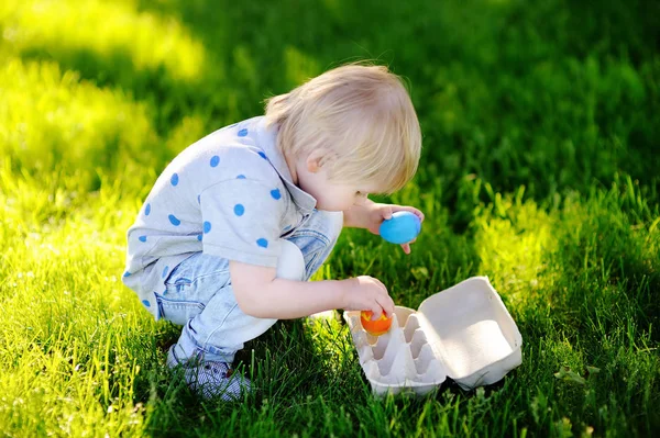 Liten pojke jakt på påskägg i vår trädgård på påskdagen — Stockfoto