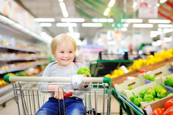 Schattig peuter jongen zitten in een supermarkt — Stockfoto