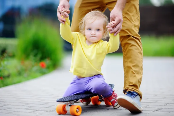 Cute girl learning to skateboard with her father — Stock Photo, Image