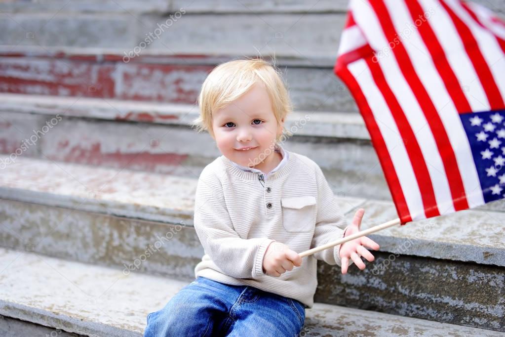Cute toddler boy holding american flag