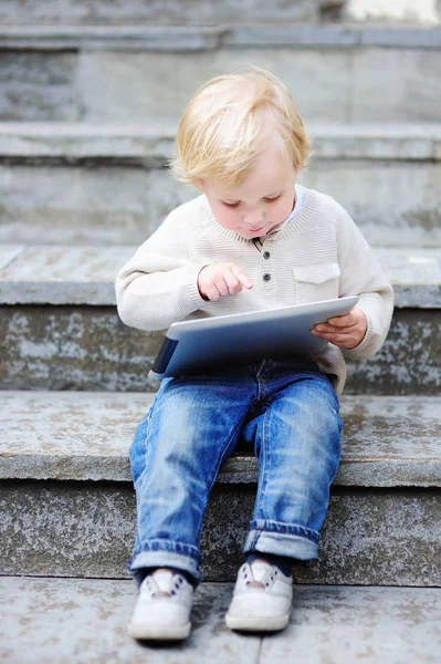 Cute blonde toddler boy playing with a digital tablet outdoors — Stock Photo, Image