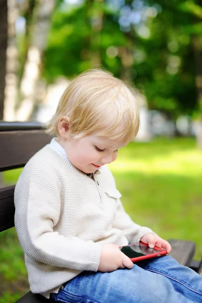 Cute blonde toddler boy playing with a digital tablet outdoors — Stock Photo, Image