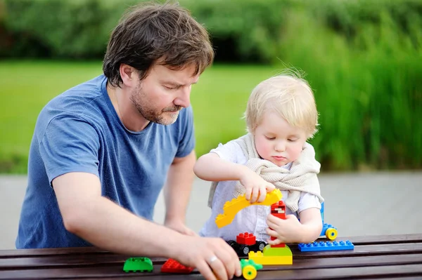 Vader met zijn peuter zoon spelen met kleurrijke kunststof blokken — Stockfoto