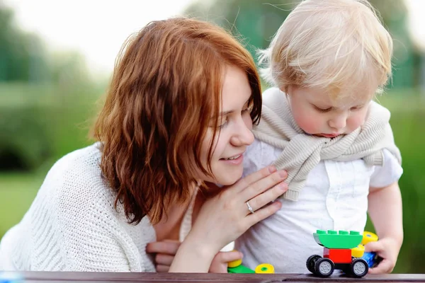 Young woman with his toddler son playing with colorful plastic blocks — Stock Photo, Image