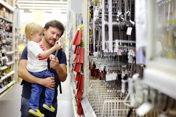 Отец и его сын выбирают нужный инструмент в хозяйственном магазине — стоковое фото