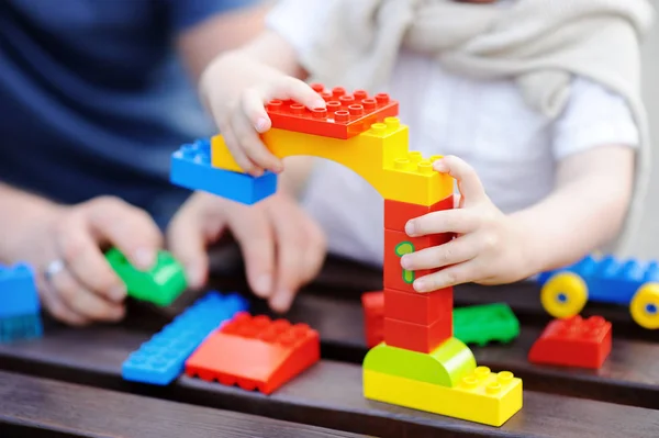 Padre con su hijo pequeño jugando con bloques de plástico de colores —  Fotos de Stock