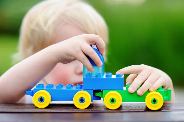 Малыш играет с игрушечным поездом на открытом воздухе — стоковое фото