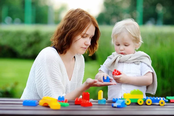 Молодая женщина со своим маленьким сыном играет с красочными пластиковыми блоками — стоковое фото