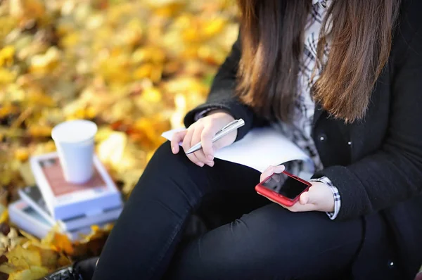 Student tjej använder sin mobiltelefon under studera — Stockfoto