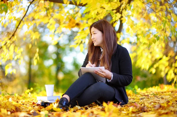 Giovane donna asiatica che studia / lavora e gode di soleggiata giornata autunnale — Foto Stock