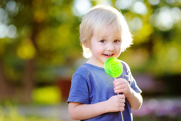 Söt liten knatte pojke med stora gröna lollipop — Stockfoto