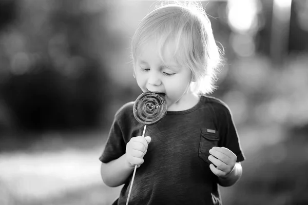 B; şirin yürümeye başlayan çocuk büyük lolipop ile ack ve beyaz fotoğrafı — Stok fotoğraf