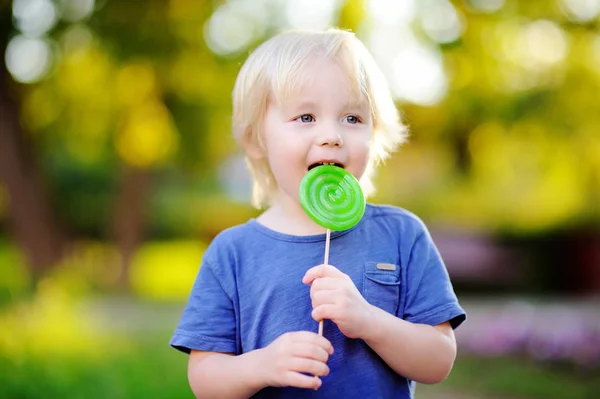 Ładny toddler chłopiec z duży zielony lizak — Zdjęcie stockowe