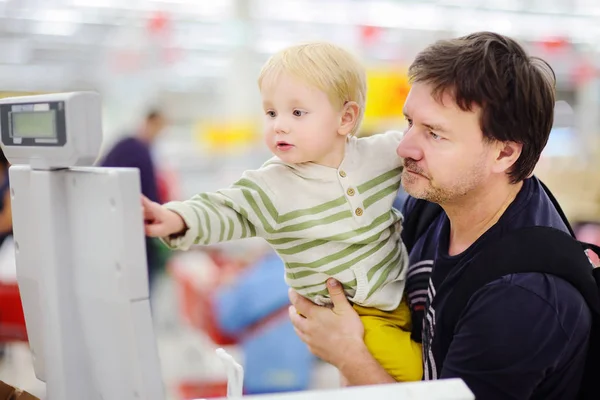 Menino bonito e seu pai de meia-idade em uma loja de alimentos ou um supermercado — Fotografia de Stock