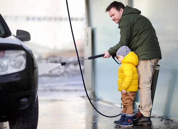 Homem de meia-idade e seu pequeno filho lavando um carro em uma lavagem de carros — Fotografia de Stock