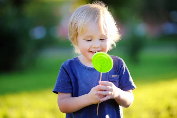 Büyük yeşil lolipop güneşli Park ile şirin yürümeye başlayan çocuk — Stok fotoğraf