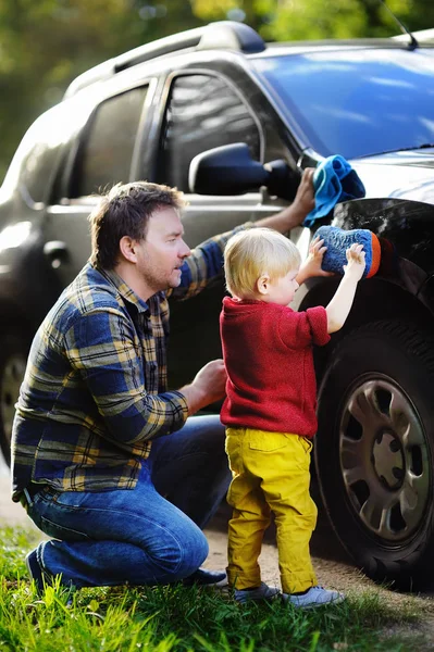 Padre de mediana edad con su hijo pequeño lavando el coche juntos al aire libre —  Fotos de Stock