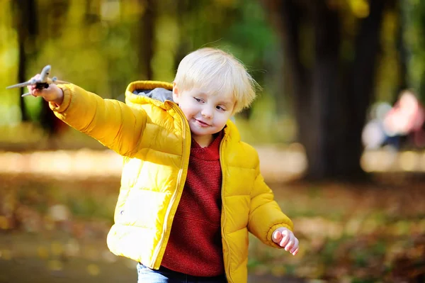 Carino bambino ragazzo giocare con giocattolo aeroplano in un autunno parco — Foto Stock