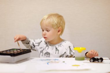 Sevimli küçük çocuk evde renkli boyalar ile çizim