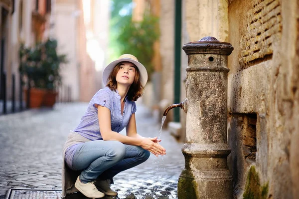 Fiatal nő tiszta ivóvíz a kúttól, Róma, Olaszország — Stock Fotó