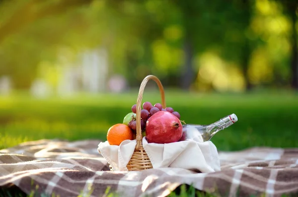 Picnic basket with fruits, food and water in the glass bottle