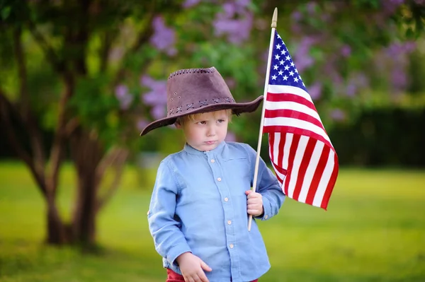 Lindo niño sosteniendo bandera americana en hermoso parque — Foto de Stock