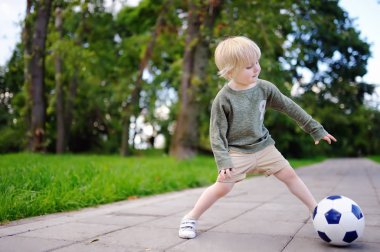 Küçük çocuk güneşli yaz gününde bir futbol oyunu oynarken eğleniyor