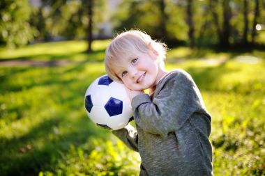 Küçük çocuk güneşli yaz gününde bir futbol oyunu oynarken eğleniyor