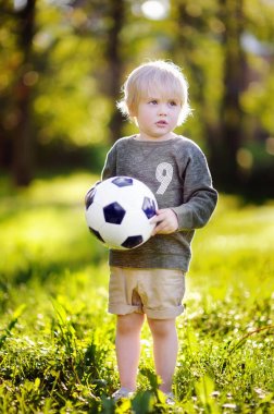 Küçük çocuk güneşli yaz gününde bir futbol oyunu oynarken eğleniyor