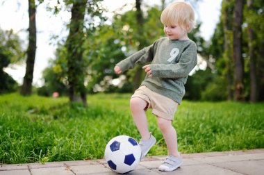 Küçük çocuk güneşli yaz gününde bir futbol oyunu oynarken eğleniyor