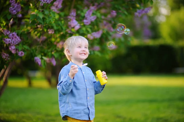 Mignon petit garçon soufflant des bulles de savon dans le beau parc d'été — Photo