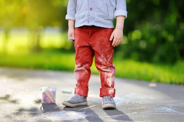 Detail fotografie malého chlapce dítě kreslení s barevnými křídami na asfaltovou. — Stock fotografie