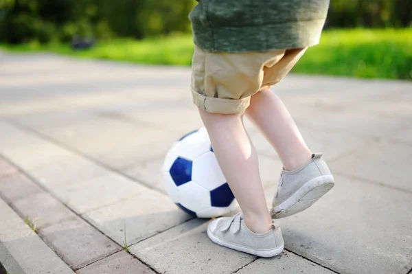 Close-up photo of little boy having fun playing a soccer game on sunny summer day