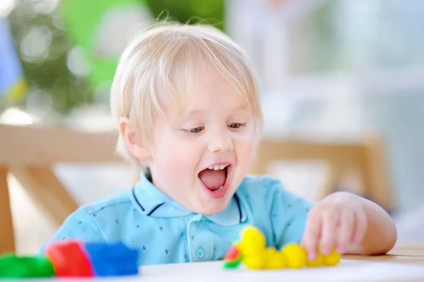 Menino criativo brincando com argila de modelagem colorida no jardim de infância — Fotografia de Stock