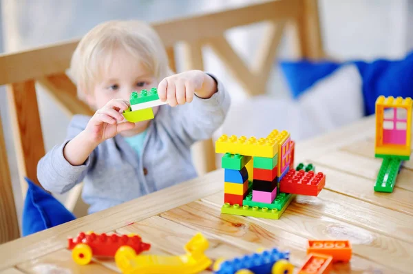 Malý chlapec hrát s barevnými plastovými bloky ve školce. — Stock fotografie