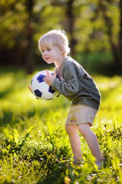 Küçük çocuk güneşli yaz gününde bir futbol oyunu oynarken eğleniyor