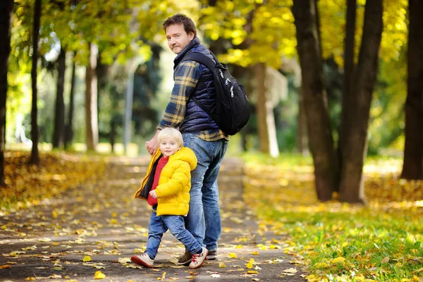 Отец и его маленький сын прогуливаются в осеннем парке — стоковое фото