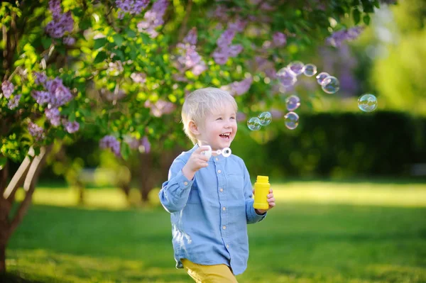 Mignon petit garçon soufflant des bulles de savon dans le beau parc d'été — Photo